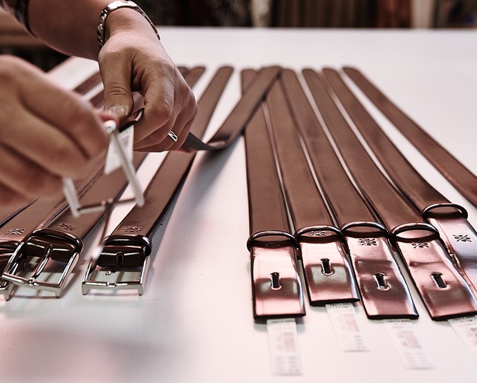 Bruna läderbälten där ett par händer sätter fast silvriga spännen